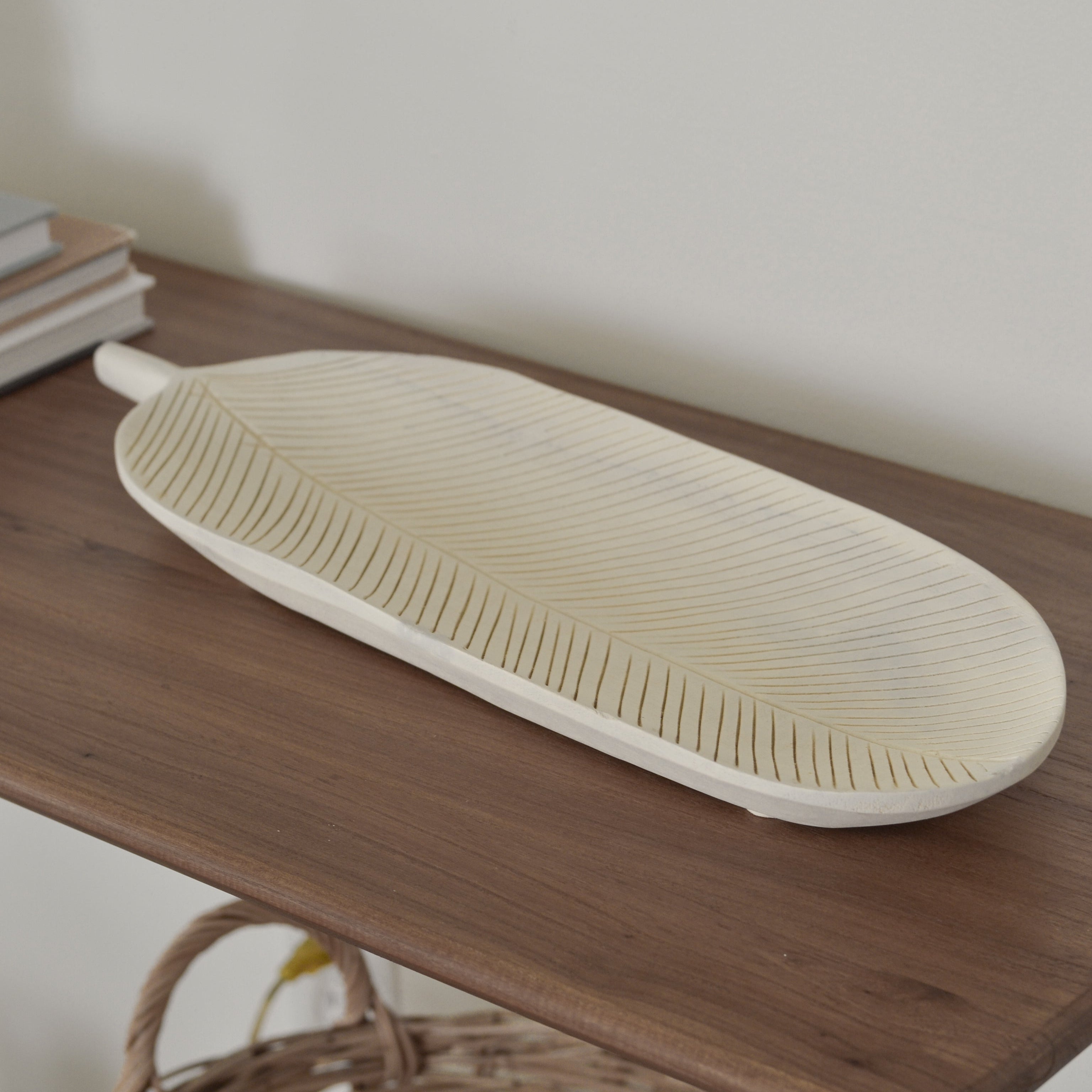Woven tray on a wooden surface with a wicker basket and books in the background.