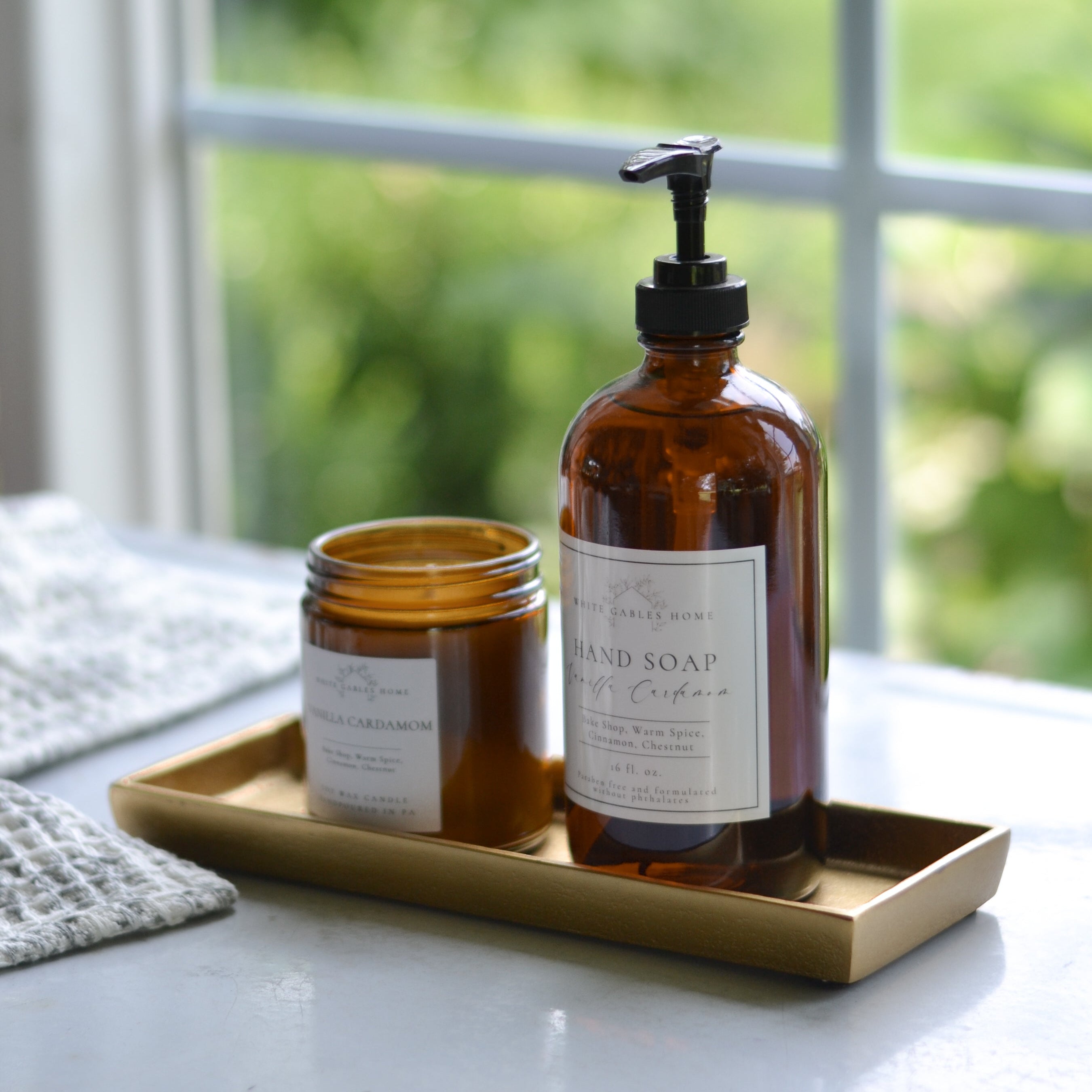Two brown bottles with pump and jar on a gold tray with a blurred green outdoor background