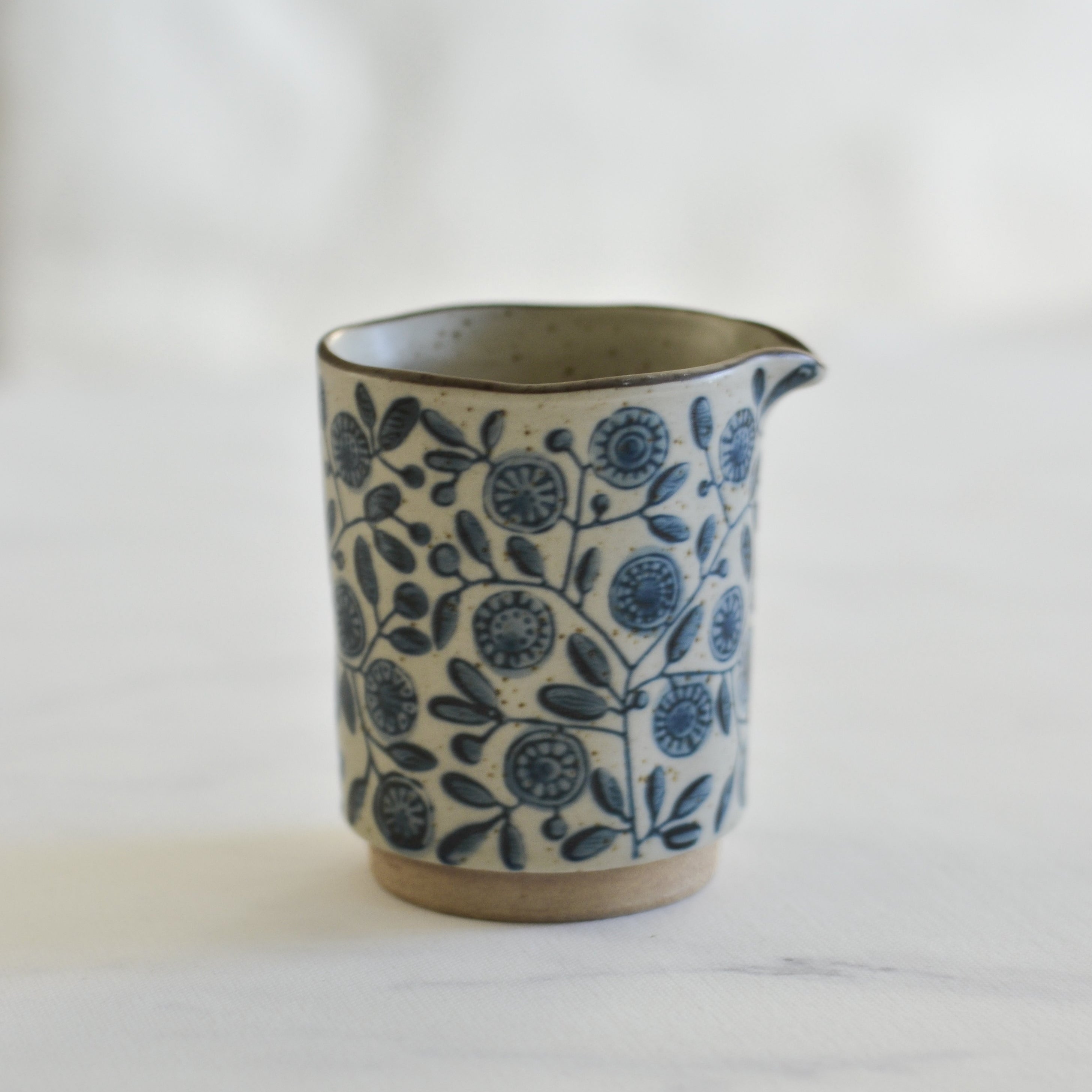 Ceramic pitcher with blue floral pattern on a white background